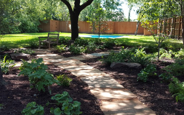 Instead of fighting with the shade in this landscape to keep trying to grow grass, which was a waste of water and fertilizer, we transformed this shady landscape into a haven for low-maintenance shade-loving plants and a place for the homeowners to cool off and relax.